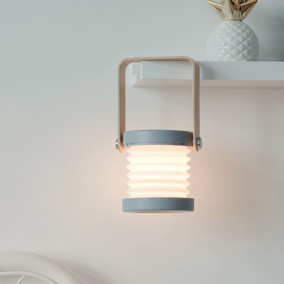 Folding lantern open and lit beside flameless candles in a dark room