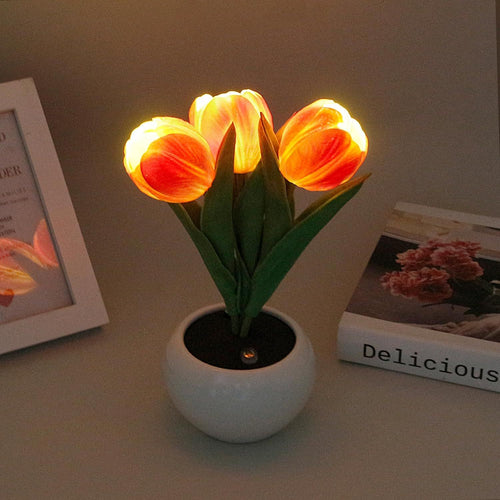 Tulip lamp in warm orange, three glowing tulips in a white pot on a desk