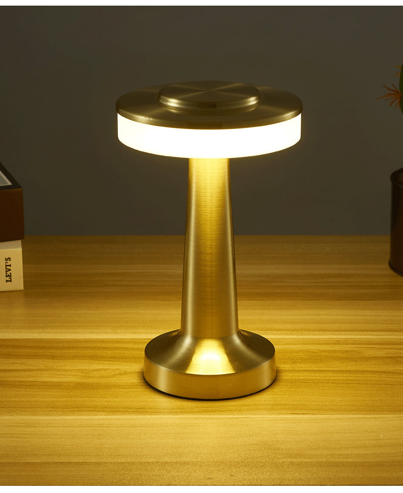 Cordless Table Lamp in gold, switched on against a warm background