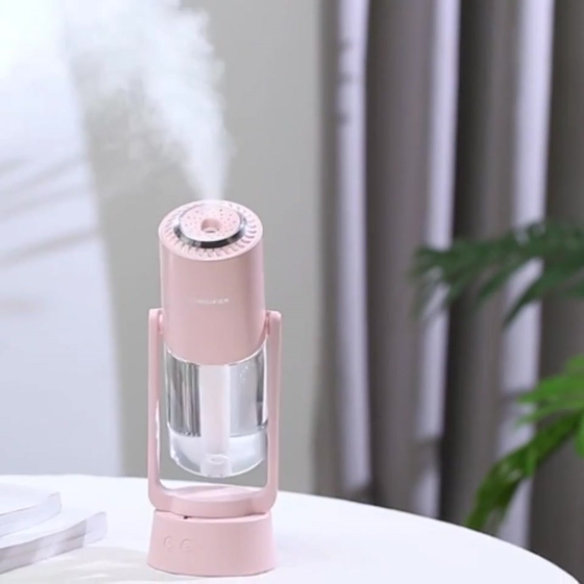 Night Mist Projector in pink with cool mist rising beside a window